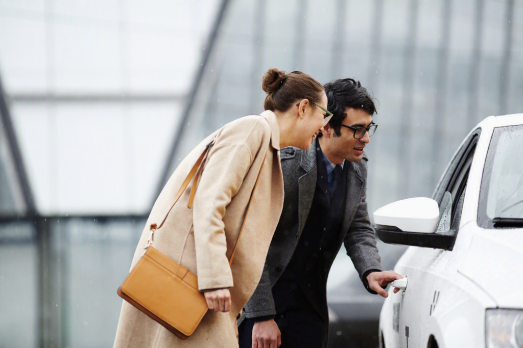 Two passengers entering a white taxi vehicle outside a modern city building for convenient and reliable transportation.